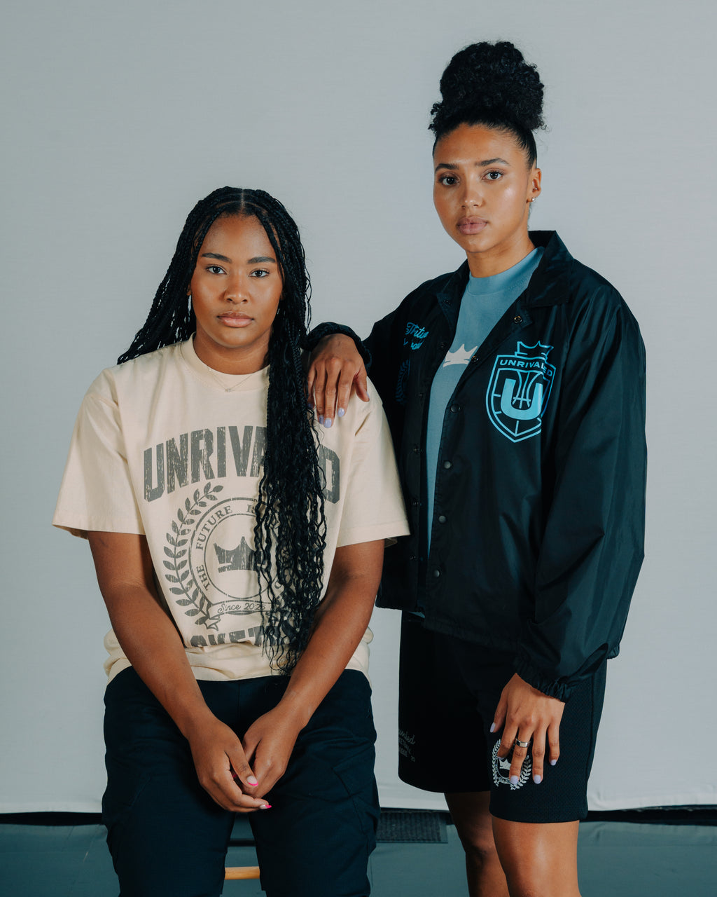 Sarah Strong and Azzi Fudd standing together. Sarah wears an oversized tan Unrivaled Basketball shirt