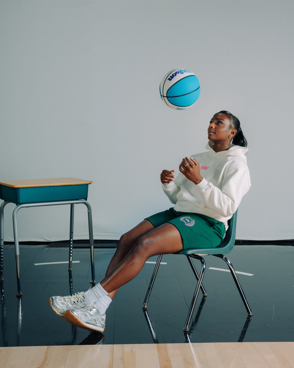 Ta’Niya Latson sitting on a chair in a white hoodie