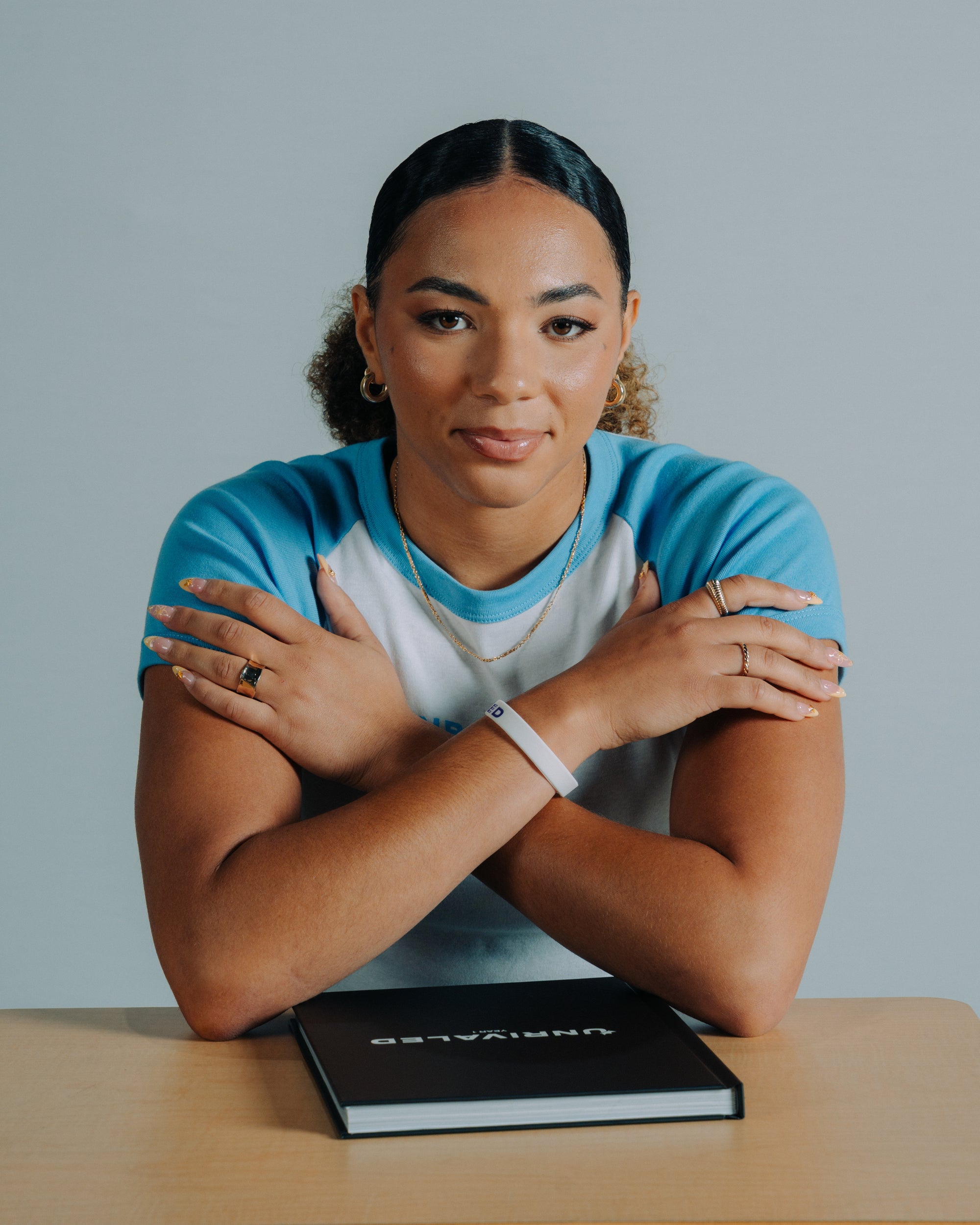 Kiki Rice with crossed arms in a Baby Blue and White Tee
